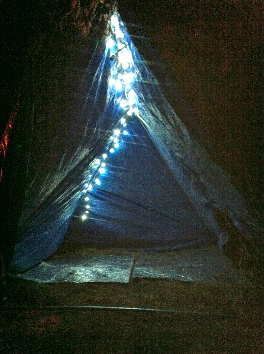 The tipi lit up, at night.