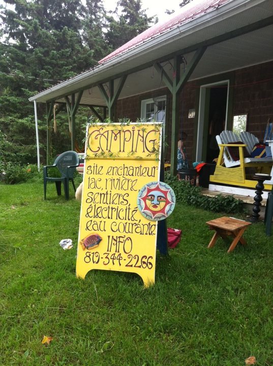 July 2011: the hand-painted sign in front of the house's porch. "Camping: enchanting site, lake, river, trails, electricity, running water."