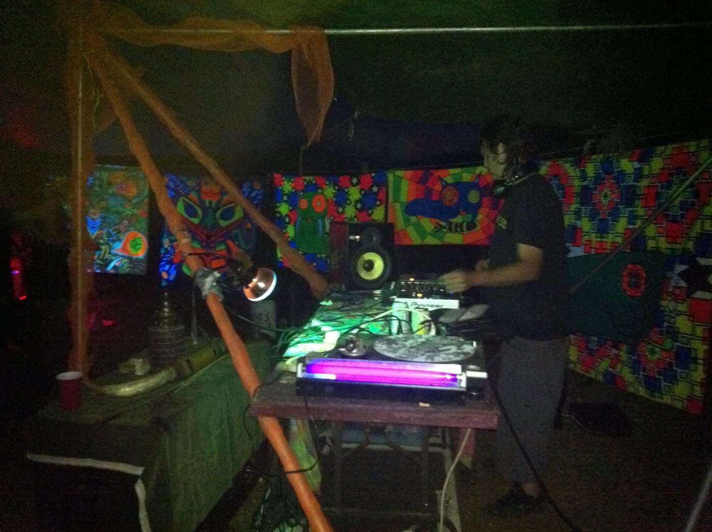 The DJ in his booth lined with psychedelic canvases.