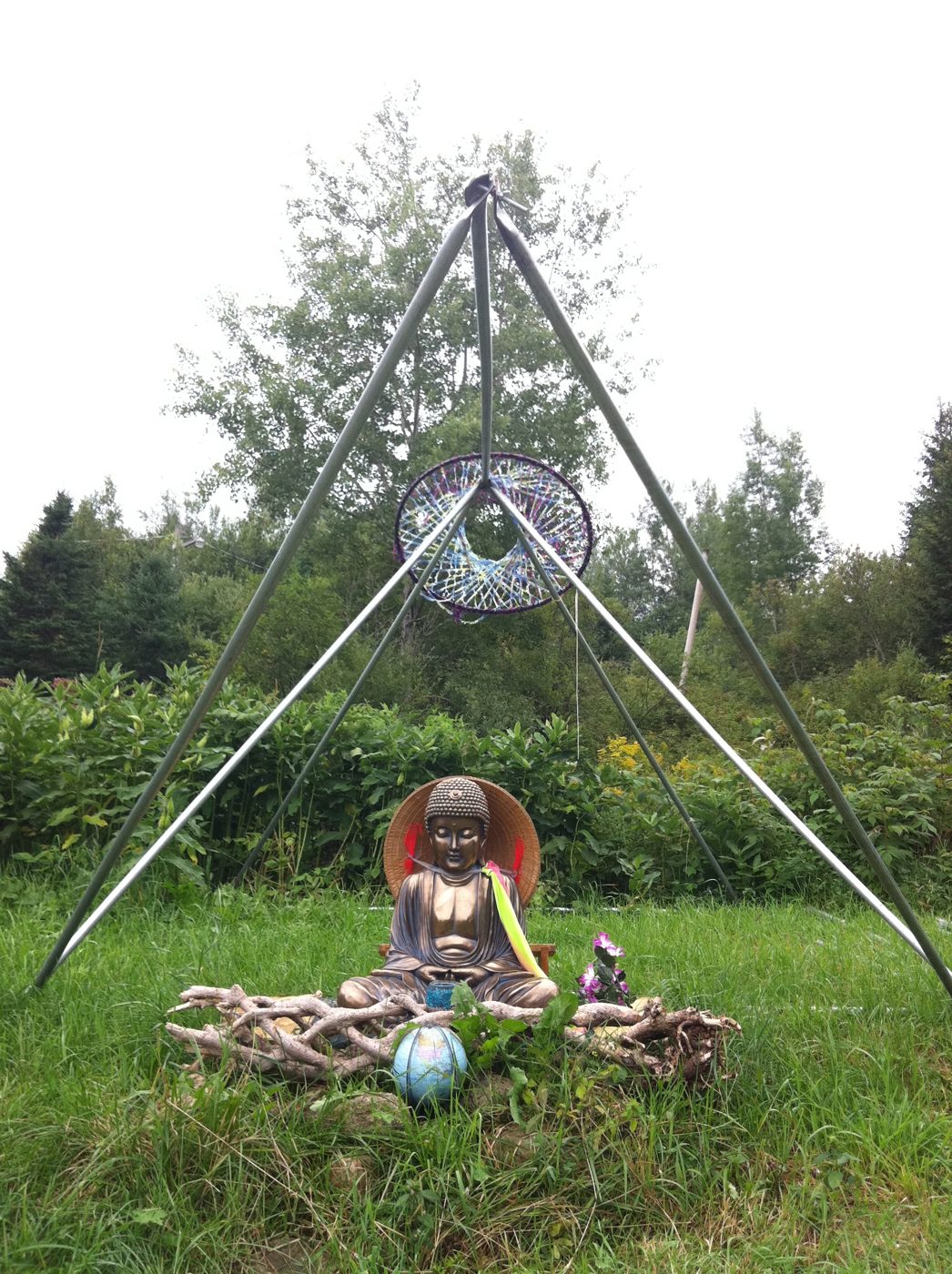 The Buddha under its tripod, in the grass.